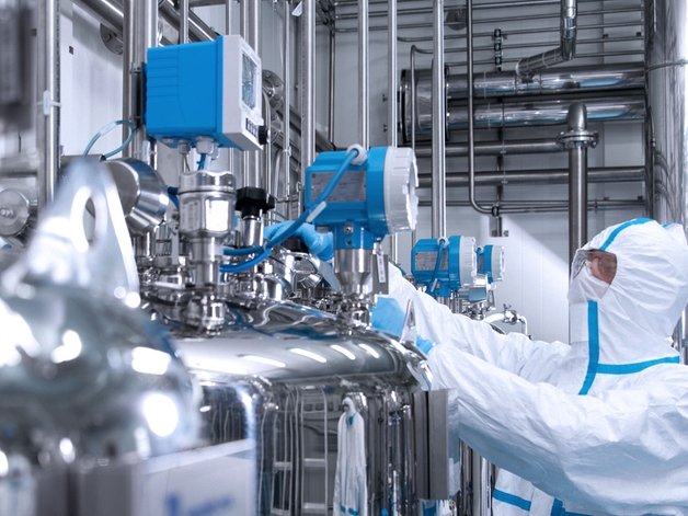 Engineer in a hygienic suit operating a device in life science environment.